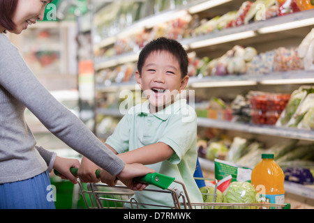 Kleiner Junge lächelnd, sitzen in einem Warenkorb Einkaufen mit Mutter Stockfoto