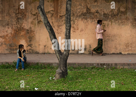 Eine Frau wacht einen Mann hinter ihr passieren, in den Gärten des Lalbagh Fort in Dhaka, Bangladesch Stockfoto