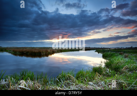 rote Sonnenstrahlen bei Sonnenuntergang vor Sturm über Fluss, Drenthe, Niederlande Stockfoto