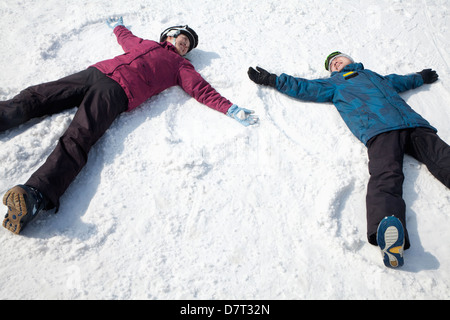 Mann und Frau liegt auf dem Schnee machen Schnee-Engel Stockfoto