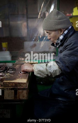 Mann, die Zubereitung von Fisch am Tsukiji-Fischmarkt, Tokyo, Japan Stockfoto