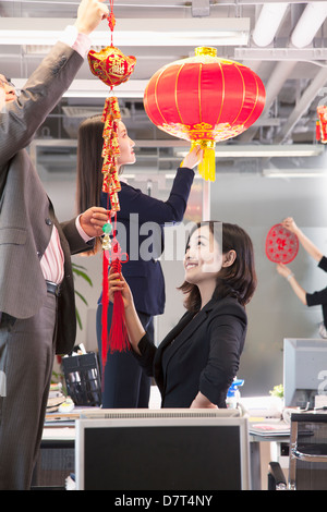 Mitarbeiter hängen Dekorationen im Amt für Chinese New year Stockfoto