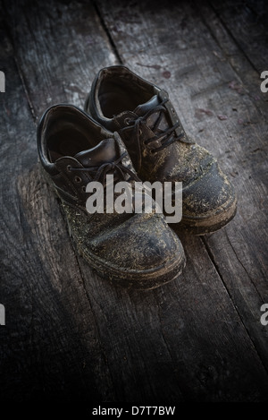 Alte dreckige Schwarze Lederschuhe auf Holzboden. Stockfoto