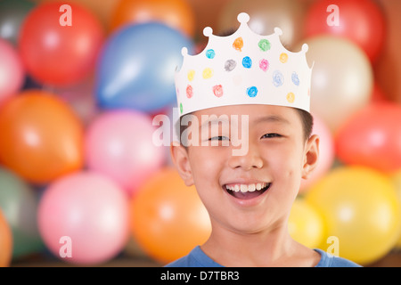 Geburtstagskind mit einer Krone vor Luftballons Stockfoto