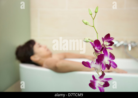 Frau Baden mit Orchidee im Vordergrund Stockfoto