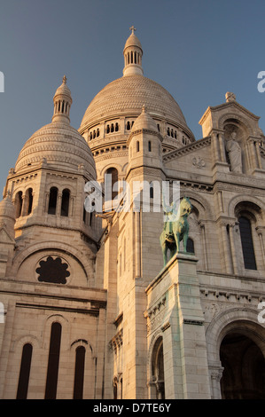 Die Fassade und die hoch aufragenden weißen Kuppeln der Basilika der Sacra-Coeur auf dem Montmartre. Über dem Portikus befindet sich eine Statue des Heiligen Ludwig. Paris, Frankreich. Stockfoto