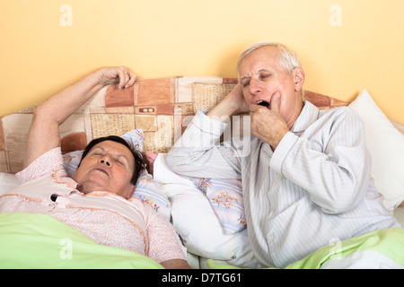 Verschlafene älterer Mann und Frau im Bett Gähnen Stockfoto