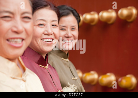 Gruppe von Reifen Frauen in traditioneller Kleidung stehen neben der traditionellen chinesischen Tür Stockfoto