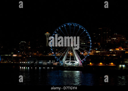 USA, WA, Seattle. Uferpromenade bei Nacht mit Lichtern auf legendären Space Needle und Seattle Great Wheel auf Pier 57 dramatische Stockfoto