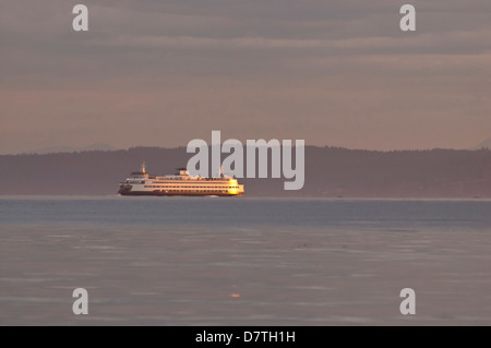 USA, WA, Edmonds. Washington State Ferry nähert sich von Kingston mit Sonnenaufgang Licht, das über Cascade Mountains Stockfoto