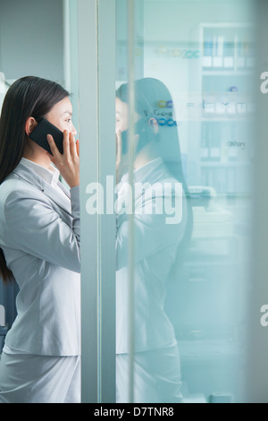 Geschäftsfrau auf Handy spiegelt sich in Glas Stockfoto