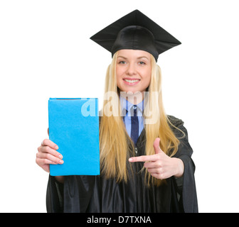 Junge Frau in Graduierung Kleid zeigt Buch Stockfoto