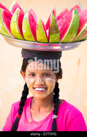 Frau mit Thanakha traditionelle Schminken, mit einem Tablett Wassermelone auf dem Kopf, Shwezigon Paya, Nyaung U, Burma Stockfoto