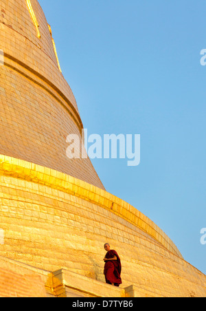 Buddhistischer Mönch zu Fuß rund um die vergoldete Kuppel der Shwedagon Paya (Pagode) in der Abenddämmerung, Yangon (Rangun), Burma Stockfoto