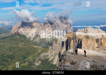 Touristen in der Nähe von Kreuz am Sass Pordoi mit Langkofel Berge in der Ferne, Berg in den Dolomiten in der Nähe von Canazei, Italien Stockfoto