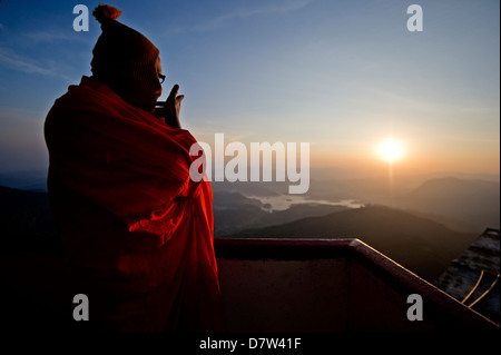 Ein Mönch blickt auf einen Sonnenaufgang von oben auf den Heiligen Berg Sri Pada (Adam es Peak), Sri Lanka Stockfoto