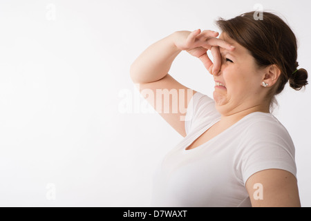 Junge Brünette kaukasischen Mädchens kneifen, halten ihre Nase zu halten, einen schlechten Geruch Geruch Stockfoto