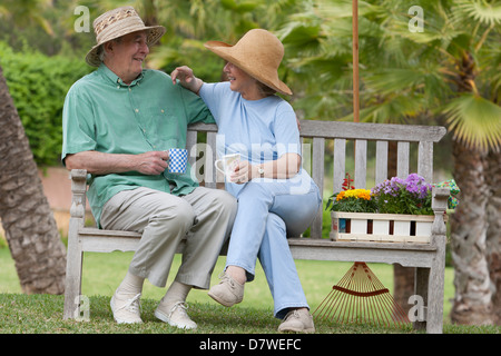 Älteres Ehepaar sitzt auf einer Bank im Garten Stockfoto