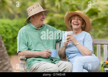 Älteres Ehepaar sitzt auf einer Bank im Garten Stockfoto