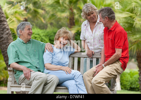 Zwei ältere Paare sitzen auf einer Bank im Garten Stockfoto