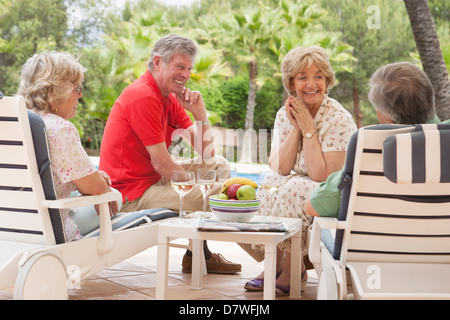 Zwei ältere Paare genießen ein Glas Weißwein alfresco Stockfoto