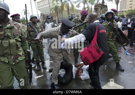 Nairobi, Kenia. 14. Mai 2013. Ein Polizeibeamter versucht zu verhindern, dass seine Offiziere gegen Aktivist Boniface Mwangi, einer der Organisatoren des Protestes '' besetzen Parlament '' war. '' Wir vergossen haben das Blut von Schweinen zu zeigen, dass die Abgeordneten gierig wie die Schweine,'' sagte Mwangi. Er und andere Organisatoren der Veranstaltung wurden verhaftet. (Bild Kredit: Kredit: Ric Francis/ZUMAPRESS.com/Alamy Live-Nachrichten) Stockfoto