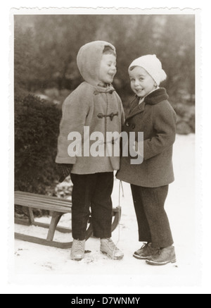 Foto von zwei glückliche junge Kinder im Schnee mit dem Schlitten, Eberswalde, Deutschland, 1930, s 1940, Zeitvertreib. Stockfoto