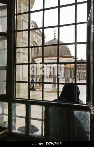 Damaskus, Syrien. Die große Omayyaden-Moschee, ein 8. Jahrhundert islamische Denkmal. Blick durch Fenster zum Hof, Frau sitzt. Stockfoto