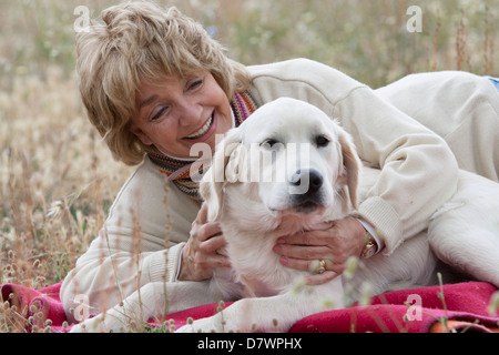 Elederly Frau liegt in einem Feld mit ihrem Hund Stockfoto