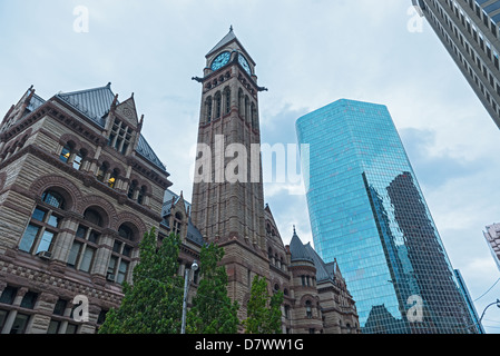 Eine Ansicht des alten Rathauses in Toronto mit modernen Bürogebäuden um ihn herum unter blauem Himmel. Stockfoto