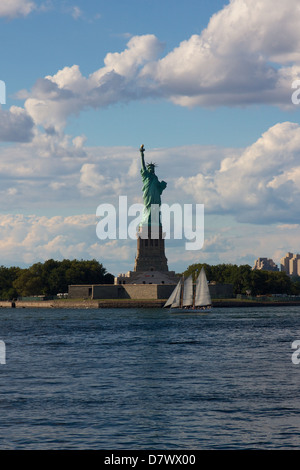 Die Freiheitsstatue auf Liberty Island, New York, NY, USA, mit einem Segelboot von davon übergeben. Stockfoto