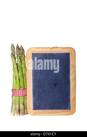Eine Handvoll frischer grüner Spargel stand neben einer alten beschreibbaren Schiefer Tafel vor weißem Hintergrund isoliert Stockfoto