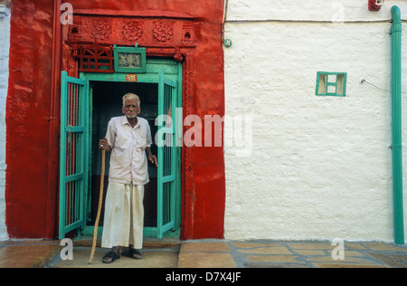 Indien, Rajasthan, Jodhpur. Ein älterer Mann mit einem Stock steht auf der Veranda seines Hauses in der Altstadt Stockfoto