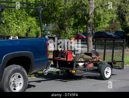 Berufslandschaftsgestalter Anhänger mit Fahrt auf Mähtraktor. Stockfoto