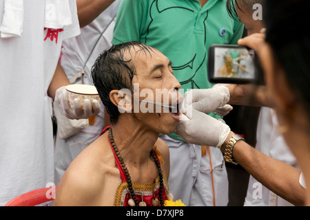 PHUKET, THAILAND - 3. Oktober 2011: A Ma Song erträgt die Schmerzen von einem Spieß Extraktion am jährlichen Phuket Vegetarian Festival. Stockfoto