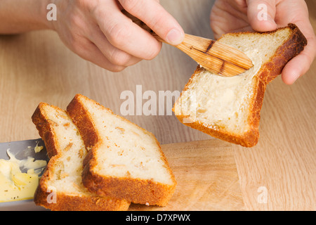 Geschmolzener Butter verteilt auf Brotscheibe beim Frühstück Stockfoto