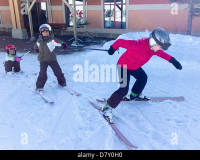 Kinder spielen auf den Skiern im verschneiten Hof Stockfoto