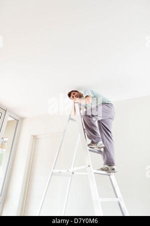 Mann Kletter Leiter im Innenbereich Stockfoto