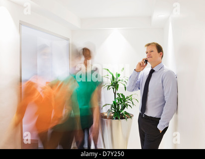 Geschäftsmann am Handy in belebten Flur Stockfoto