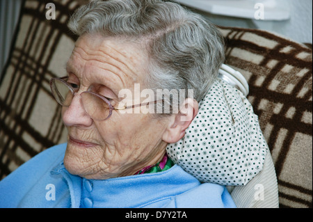 Ältere Frau mit einer Wärmflasche für Hals & Schulter Schmerzen Stockfoto