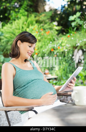 Schwangere Frau mit Tablet-PC im freien Stockfoto