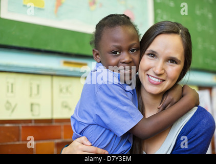 Lehrer umarmt Schüler in der Klasse Stockfoto