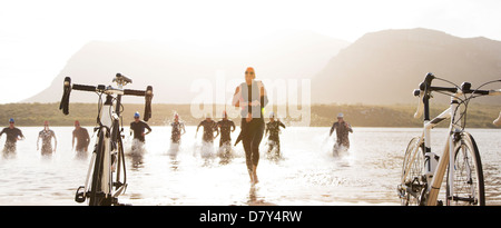 Triathleten Fahrräder am Strand laufen Stockfoto