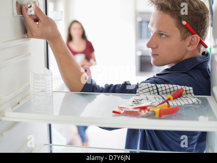 Elektriker arbeiten am Kühlschrank im Haus Stockfoto