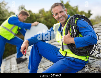 Arbeitnehmer, die Installation von Sat-Schüssel auf Dach Stockfoto