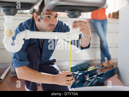Klempner Arbeiten an Rohren unter Spülbecken Stockfoto