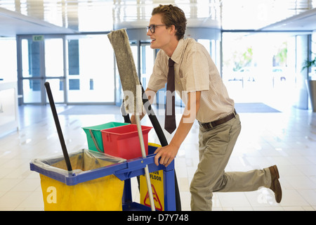 Geschäftsmann drängen Reinigungswagen im Büro Stockfoto