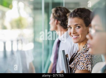 Geschäftsfrau, die lächelnd an Bürofenster Stockfoto