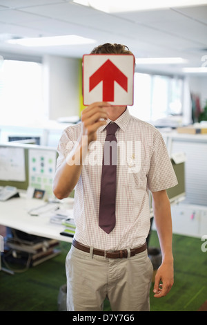 Geschäftsmann mit Pfeil Schild im Büro Stockfoto