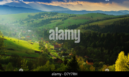 Frühling am Morgen ländlichen Landschaft in den Karpaten. Dramatischer Himmel vor der Morgendämmerung bricht ein Lichtstrahl durch die Wolken. Stockfoto